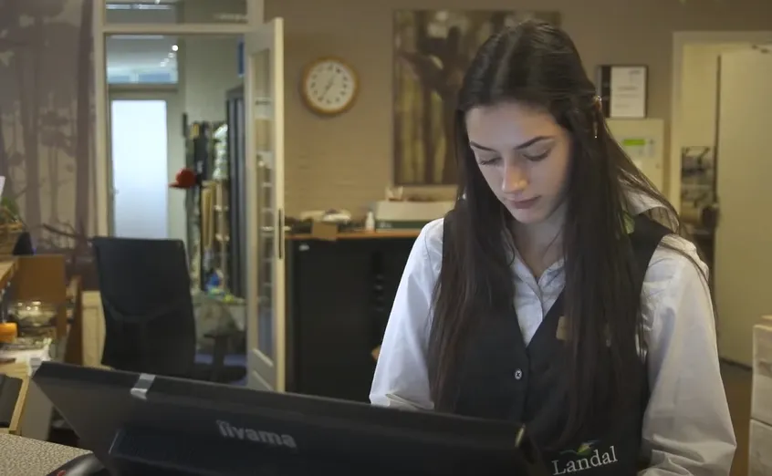 Meisje in wit overhemd achter de balie in een hotel