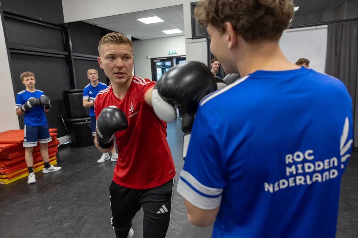Docent geeft boksles aan studenten Sport College
