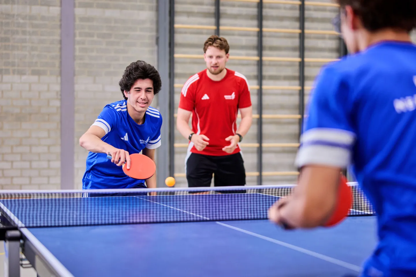 Docent moedigt sportstudenten aan tijdens tafeltennis