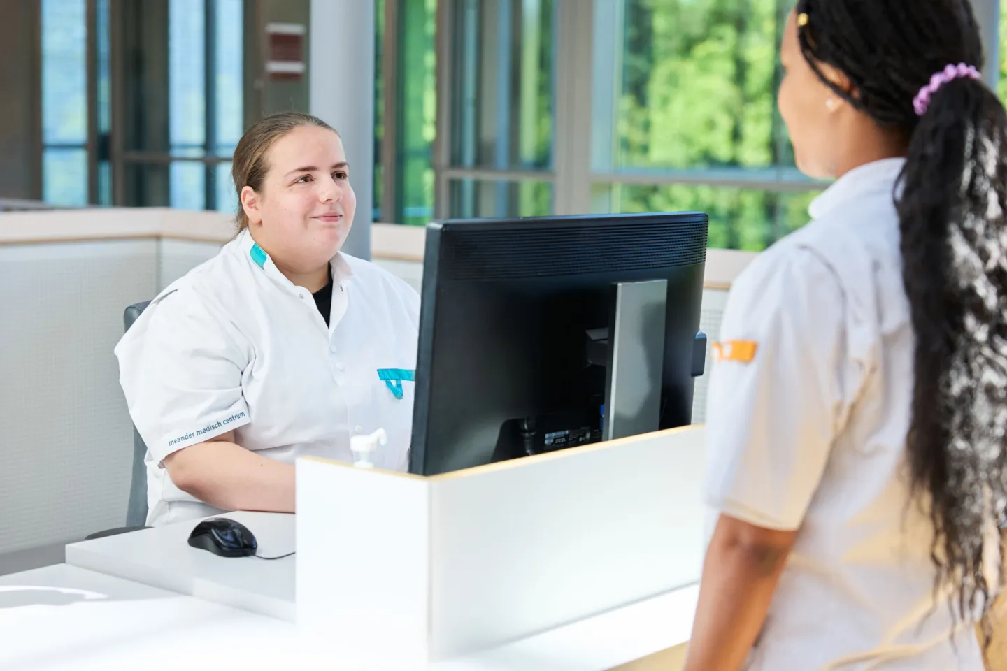 Doktersassistent overlegt aan balie met een collega