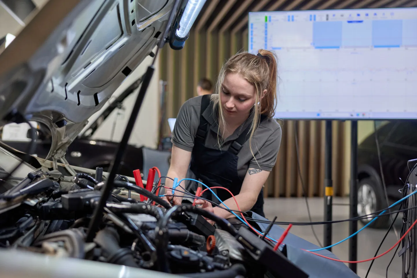 Student Autotechniek controleert elektriciteit onder de motorkap van een personenauto
