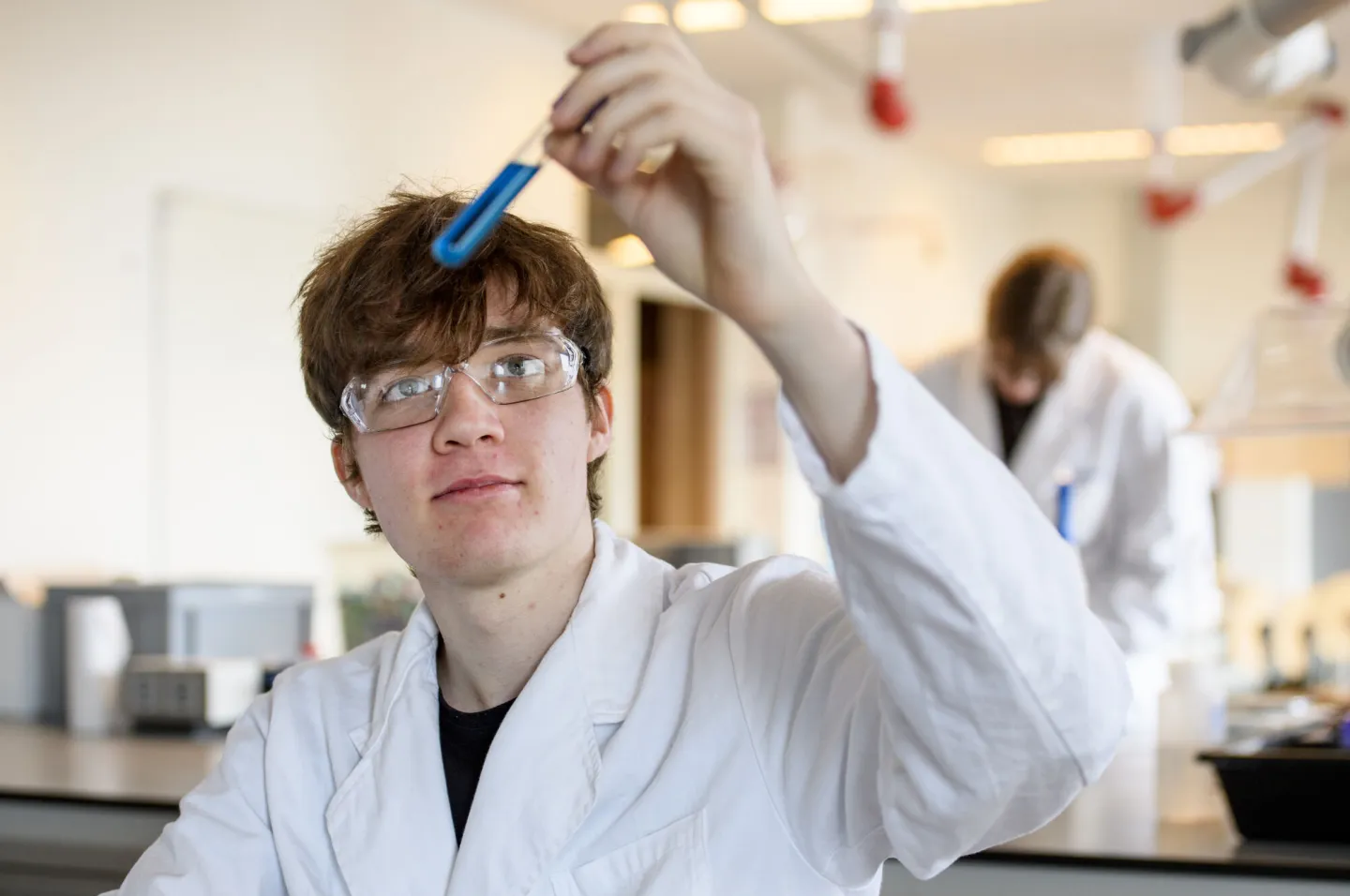 Een jonge man in een laboratoriumjas houdt een reageerbuis vast.