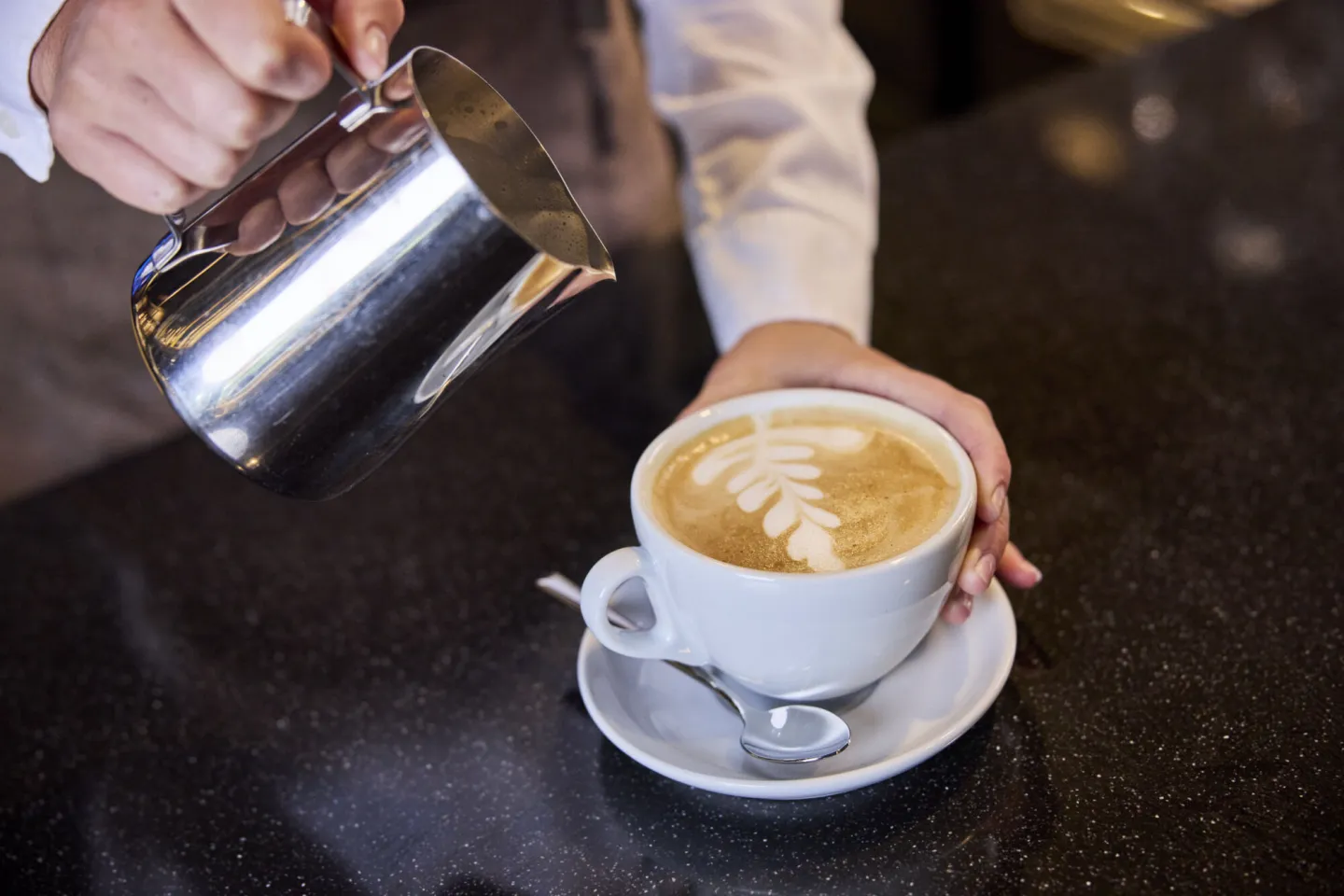 Student bereidt cappuccino voor klant in leerrestaurant