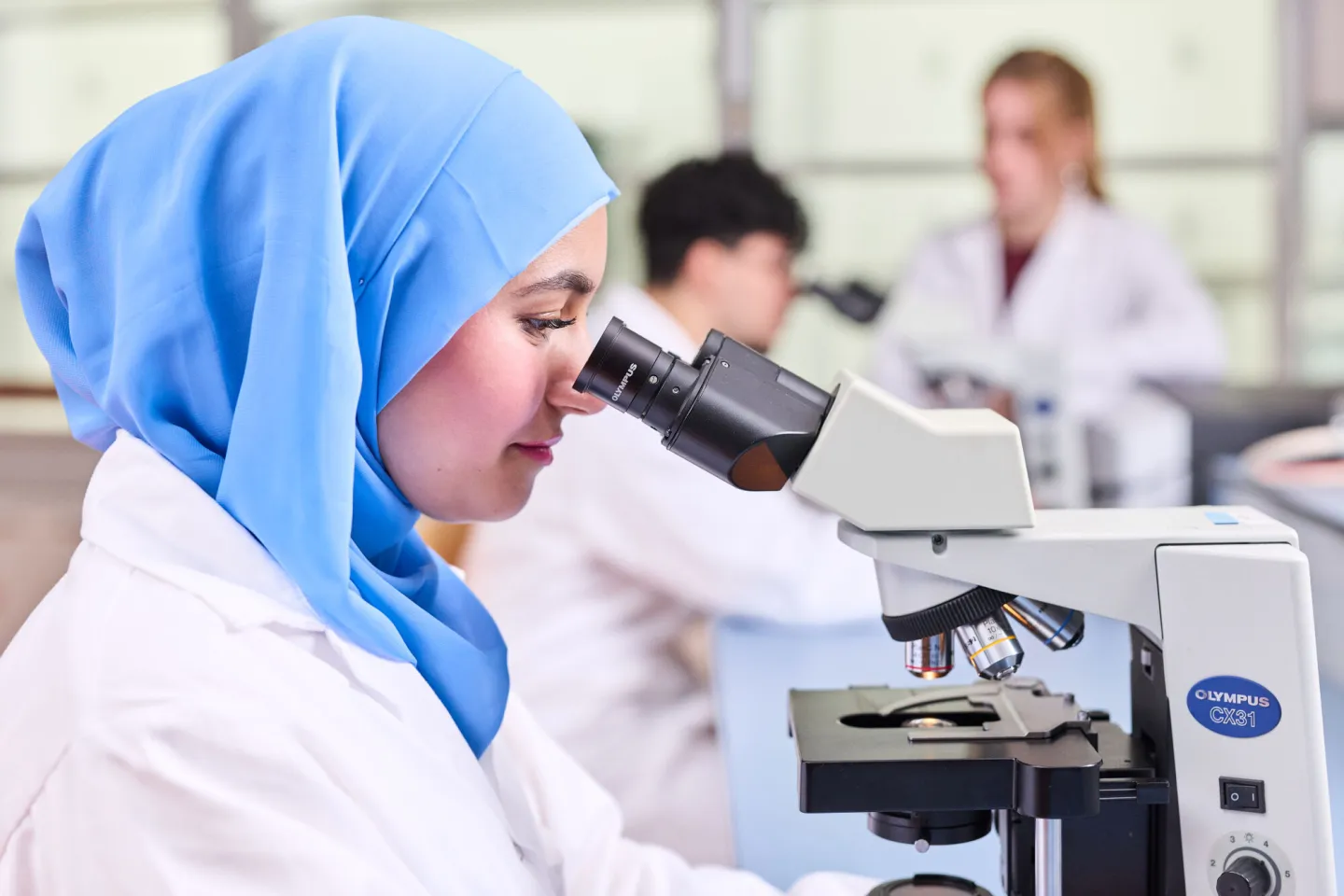 Student Analist kijkt in microscoop in het praktijklokaal