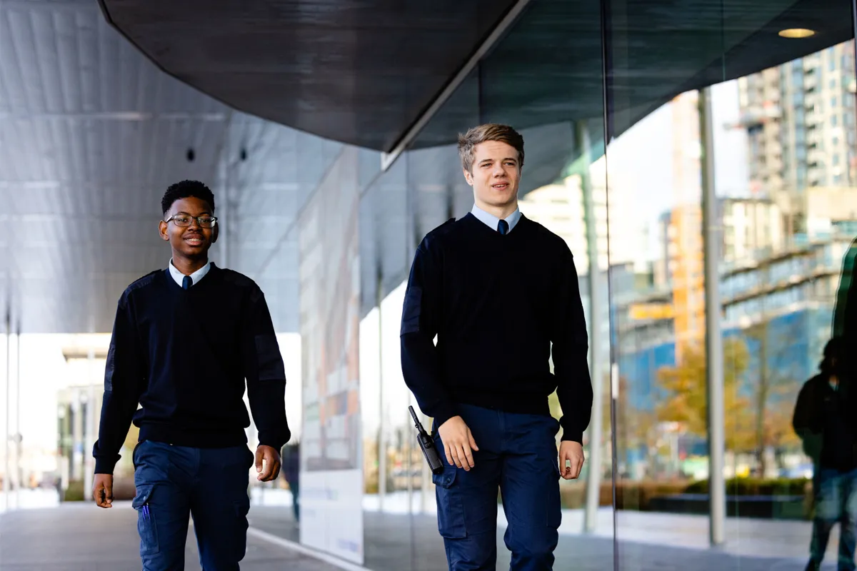 Twee studenten van de opleiding Beveiliger lopen in uniform tijdens een praktijkoefening