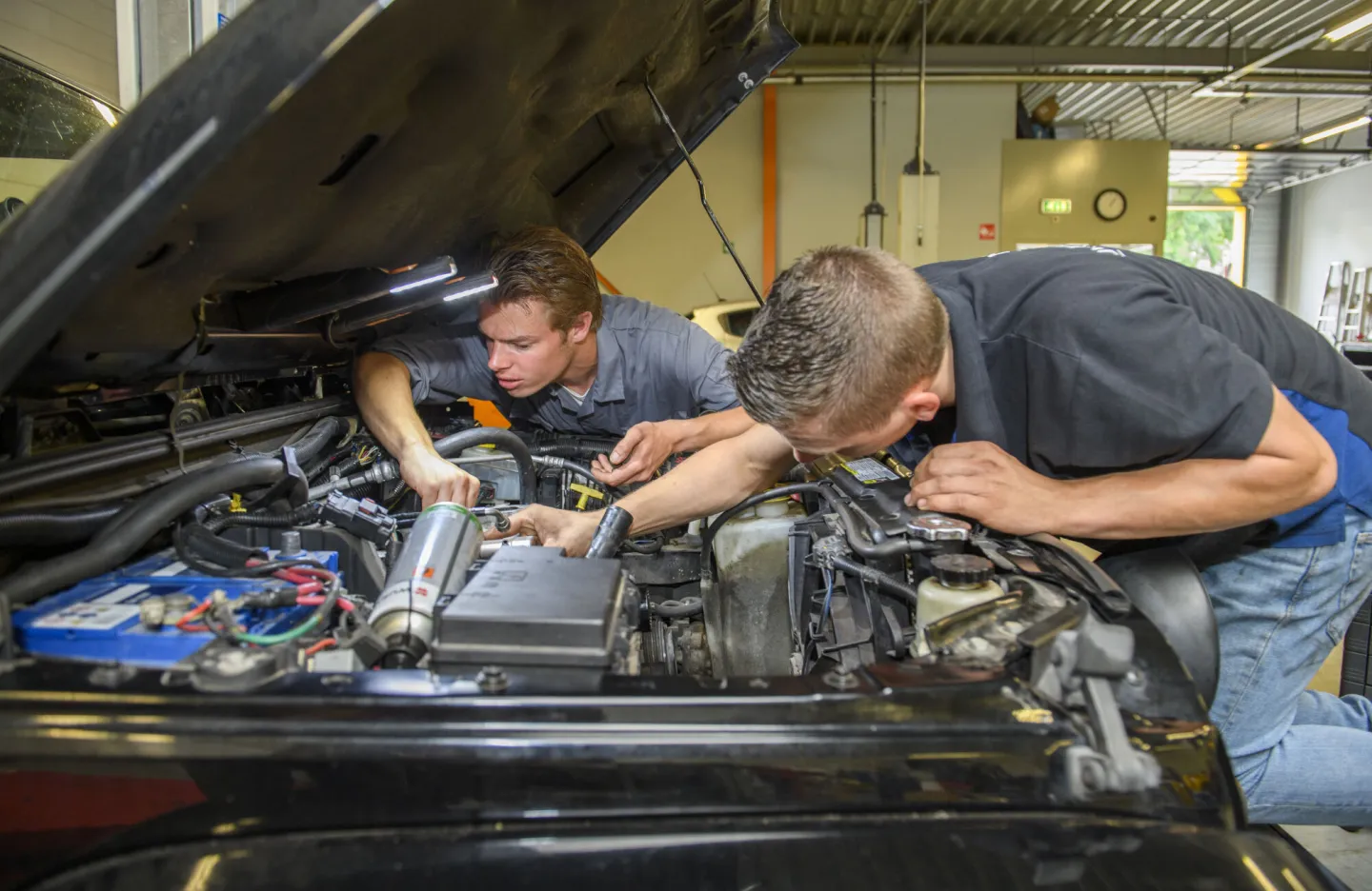 Studenten Autotechniek aan het werk onder de motorkap van een auto