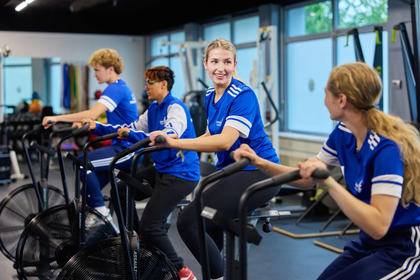 Sportstudenten hebben plezier op crossfietsen in fitnessruimte