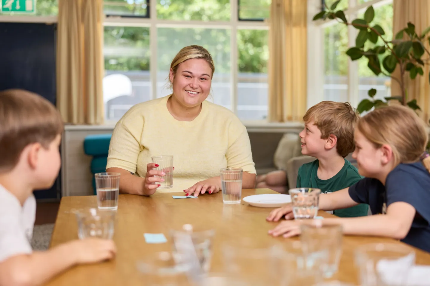 Student aan tafel met kinderen kinderopvang