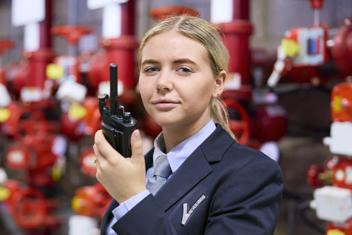 Student van de opleiding Beveiliger houdt een portofoon vast bij een technische installatie