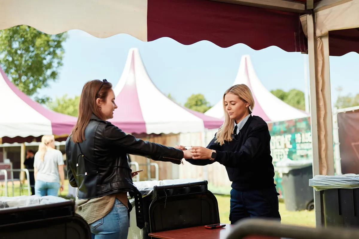 Student van de opleiding Beveiliger controleert een toegangsbewijs tijdens een praktijkoefening op een evenement