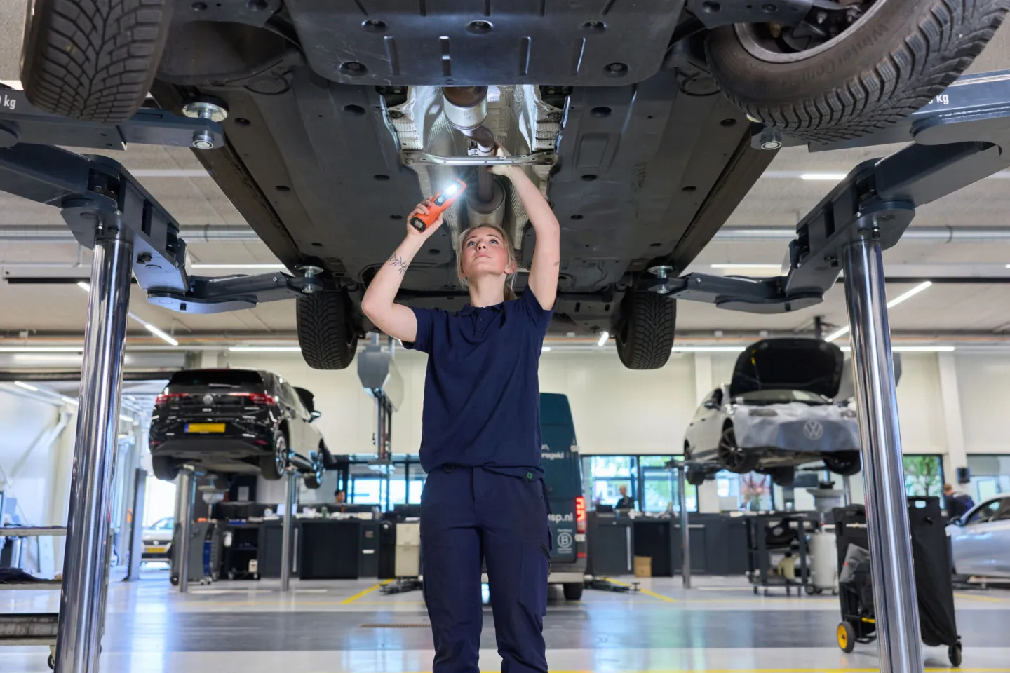 Student Autotechniek controleert onderkant auto met licht