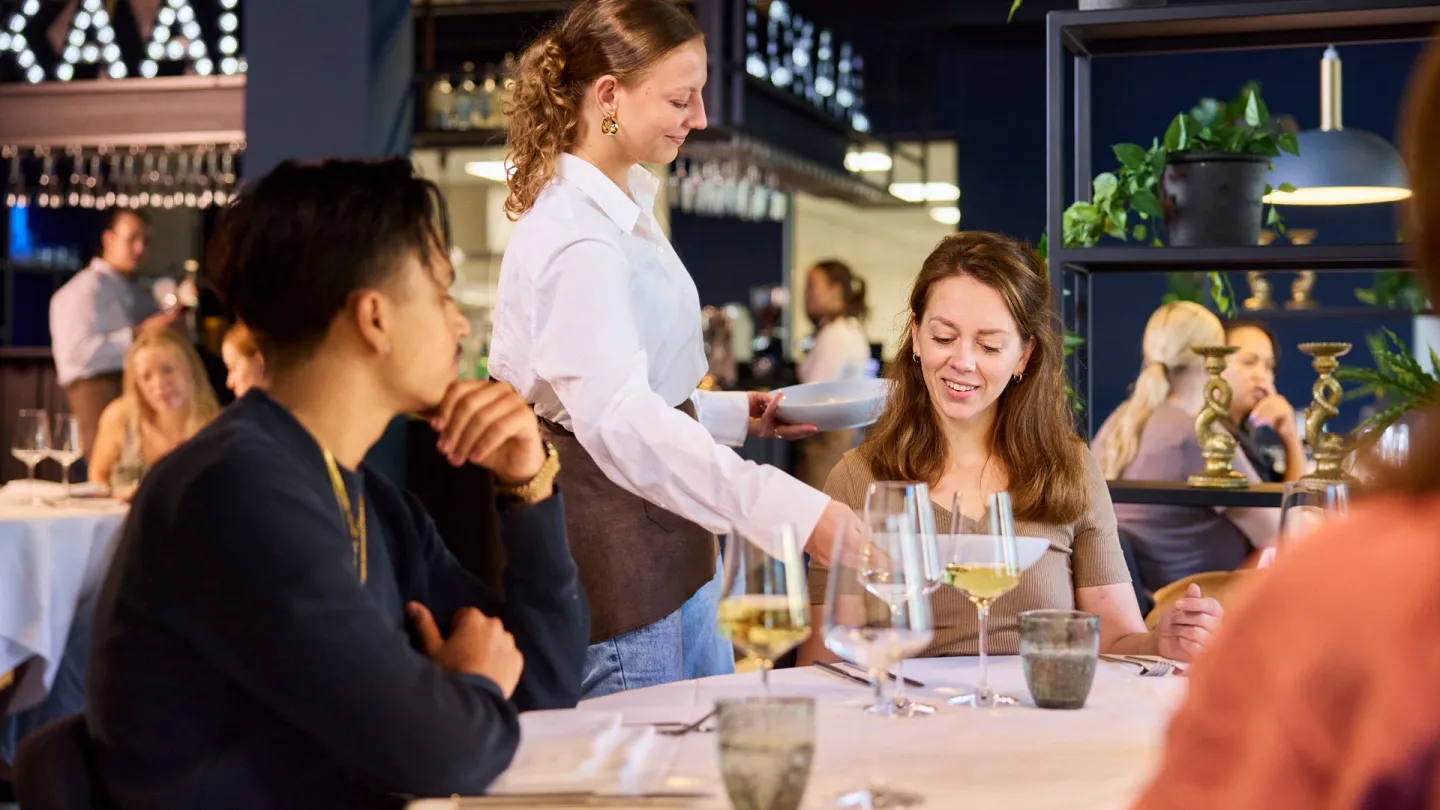 Student Gastheer/Gastvrouw bedient gasten in leerrestaurant Lokaal