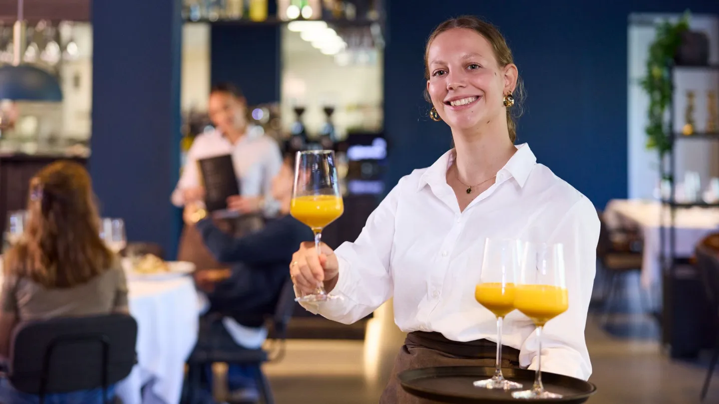 Student Gastheer/Gastvrouw serveert jus d'orange aan gasten