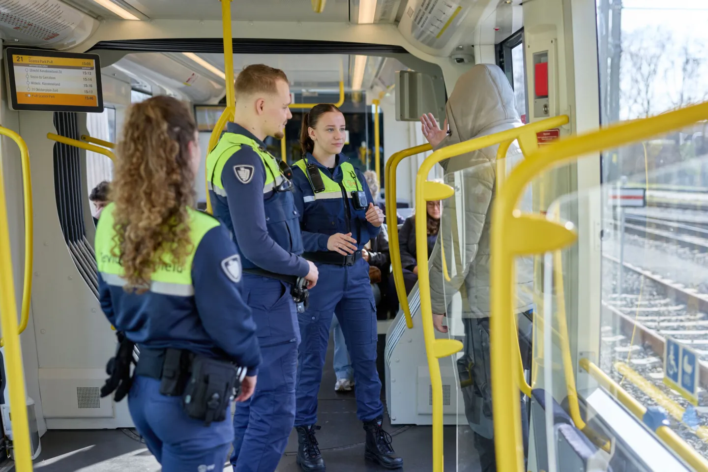 Student Handhaving praat samen met ov-boa's met reiziger die overlast geeft