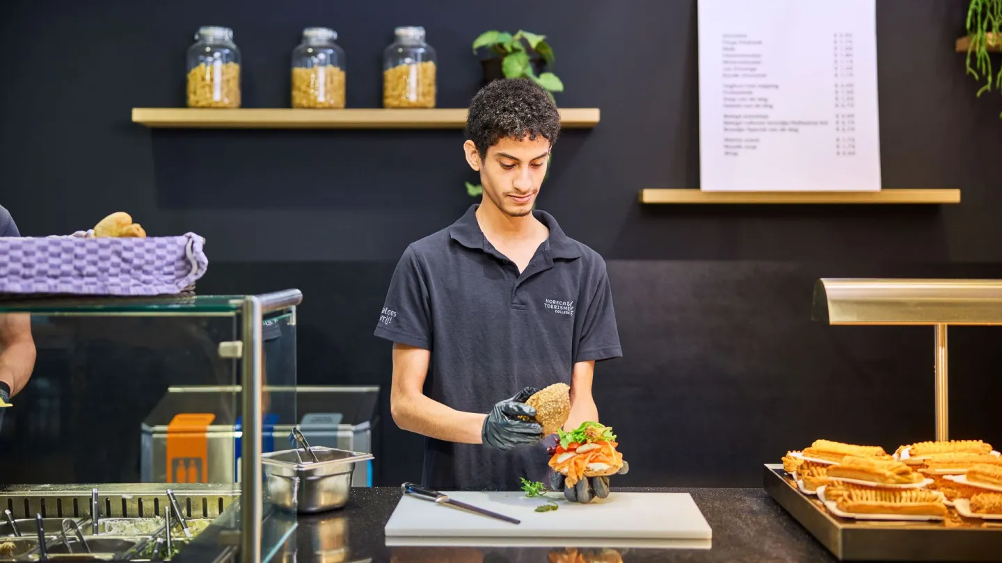 Student horeca bereidt broodje aan broodbar