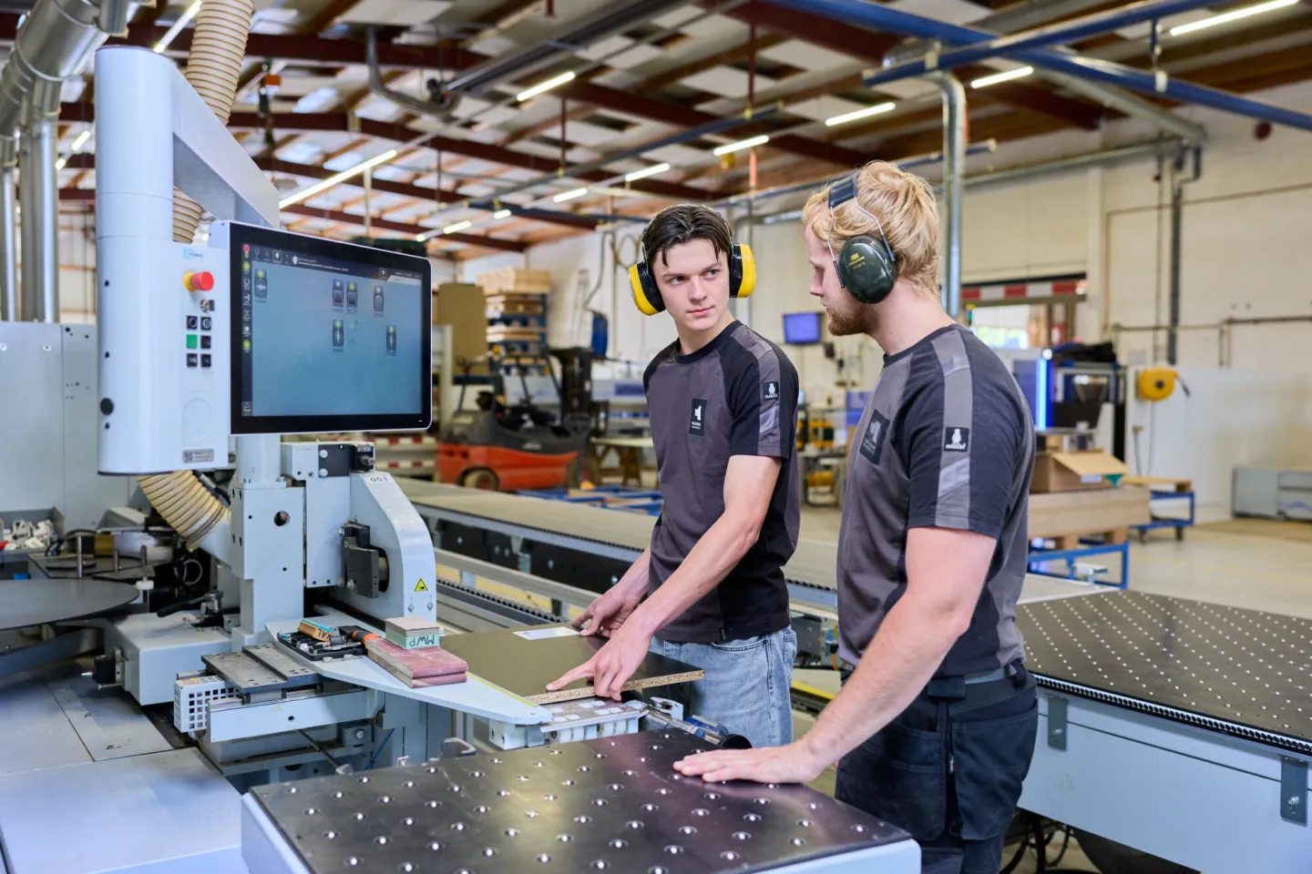 Student Meubelmaken voert werkoverleg met collega bij cnc machine