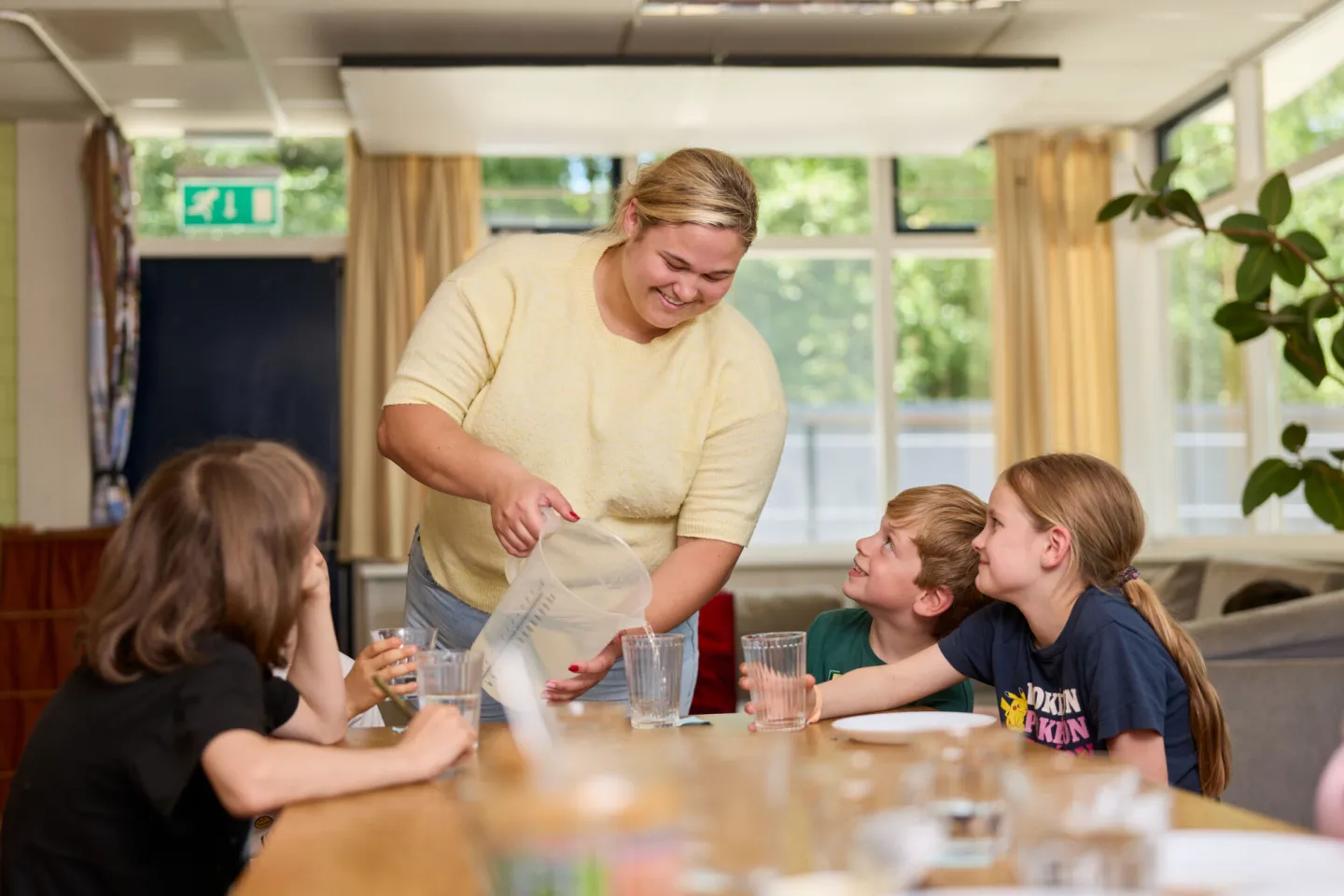 Student schenkt water in voor kinderen kinderdagverblijf kinderopvang