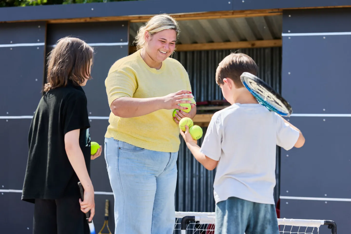 Student stagiaire deelt tennisballen uit
