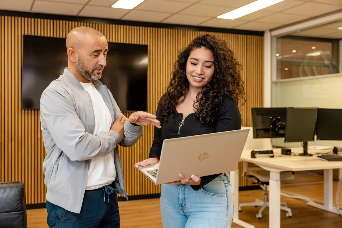 Student met laptop in haar hand aan het overleggen met docent.