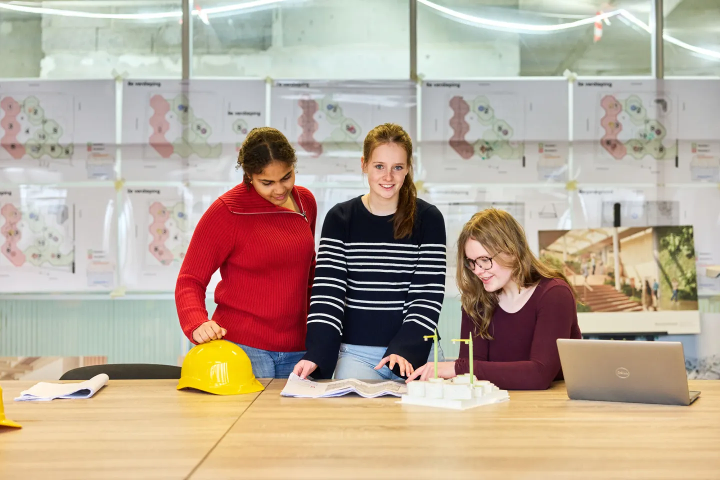 Studenten bekijken samen bouwtekeningen en maquette