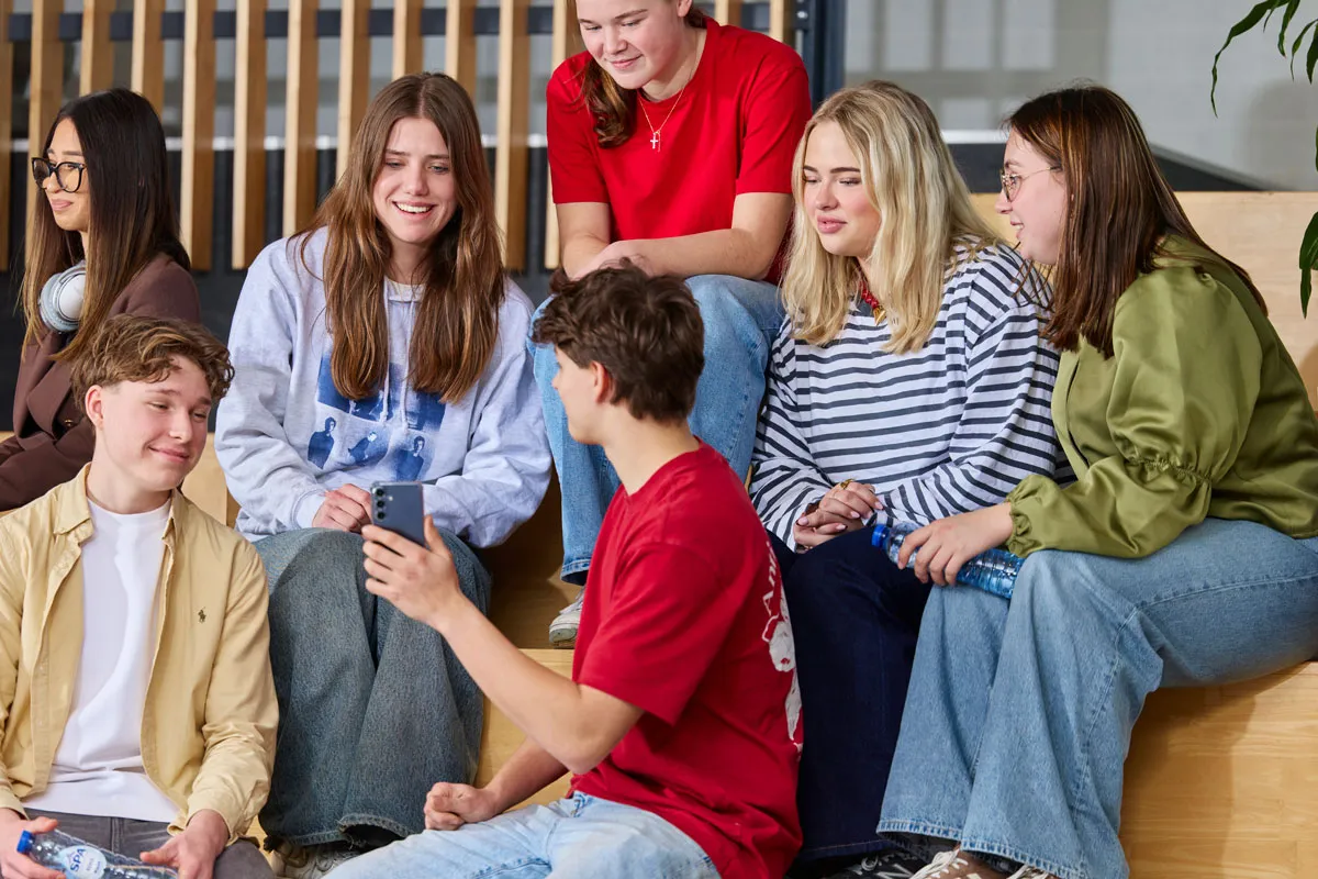 Een groep studenten zit op een trap en praat gezellig met elkaar
