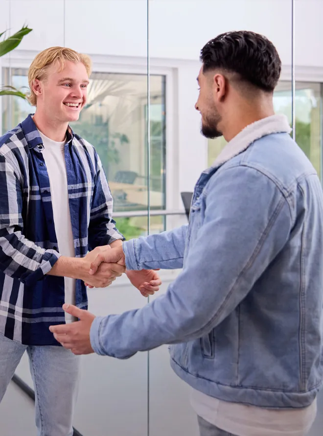 Twee studenten sluiten een deal en geven elkaar een hand in klaslokaal