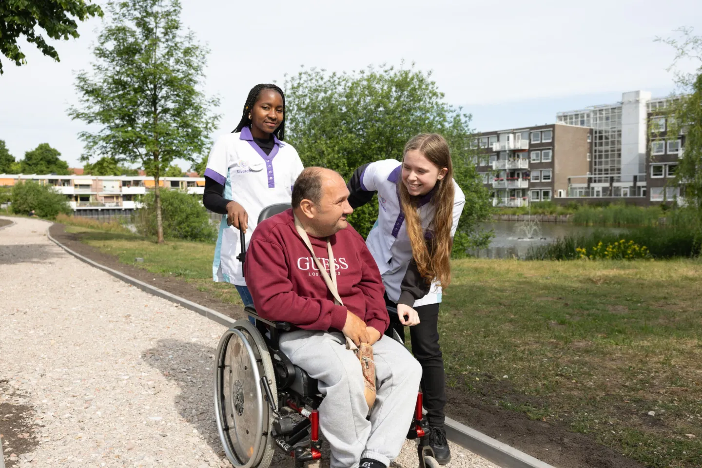 Studenten Flexopleiding Medewerker Helpende Zorg praten buiten met bewoner in rolstoel