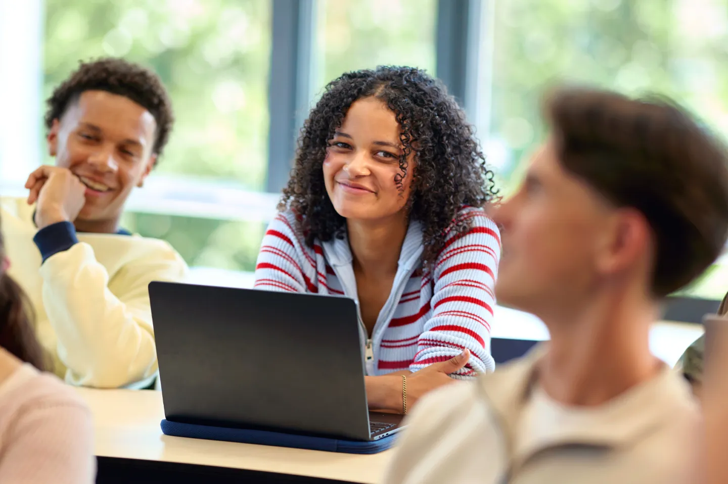 Studenten zitten in een klaslokaal met een laptop.