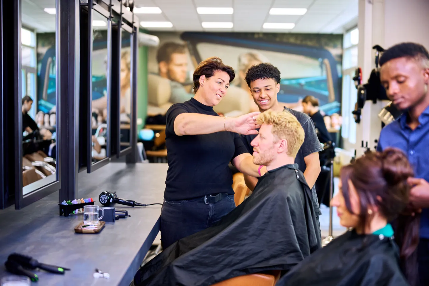 Docent Haarverzorging instrueert studenten op het Beautyplein