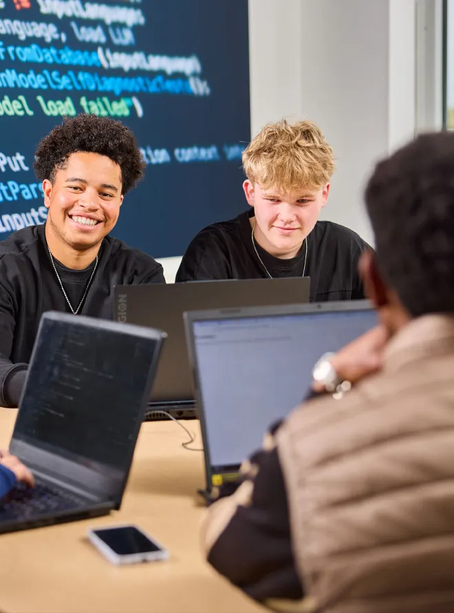 Studenten werken samen met laptops tijdens programmeerles in klaslokaal