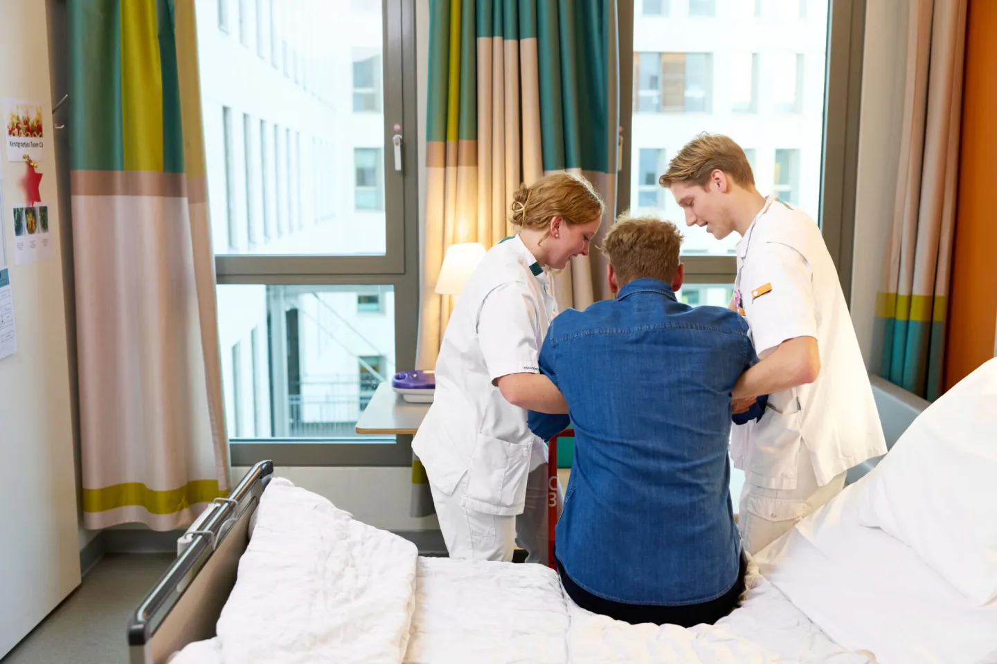 Studenten Verpleegkunde helpen patiënt uit bed