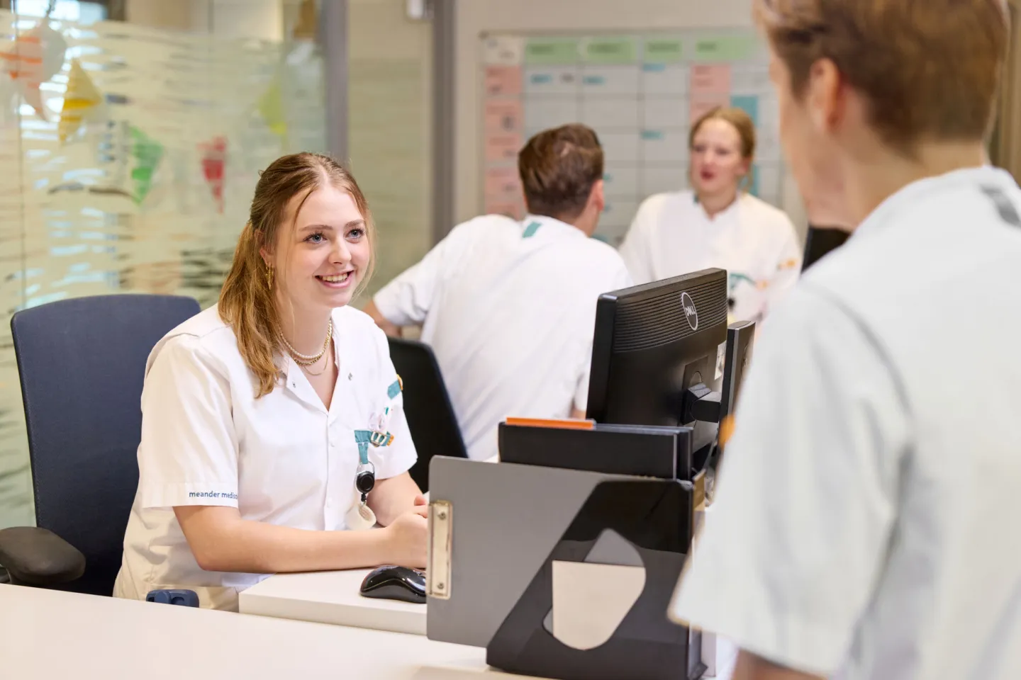 Studenten Verpleegkundige overleggen bij balie ziekenhuis