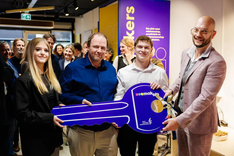 Studenten met wethouder openen winkel met grote blauwe sleutel