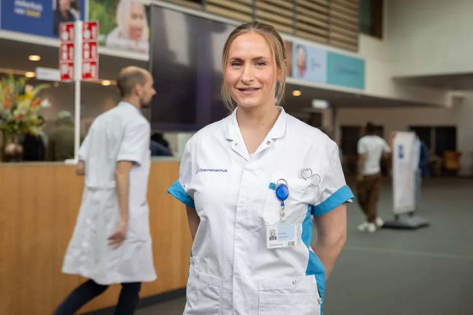 Naomi van Toor, oud-student opleiding Doktersassistent, staat voor balie in ziekenhuis.
