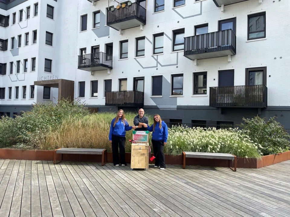 Studenten van het Bouw & Interieur College overhandigen een plandelbak aan een buurtbewoner in het Hoefkwartier in Amersfoort.