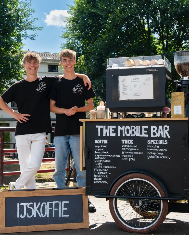 Twee mensen staan naast de mobiele koffiebar te poseren