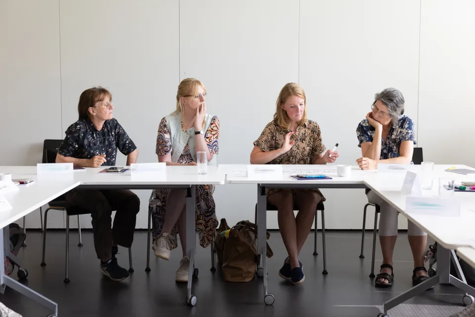 Vier volwassen studenten zitten in leslokaal.