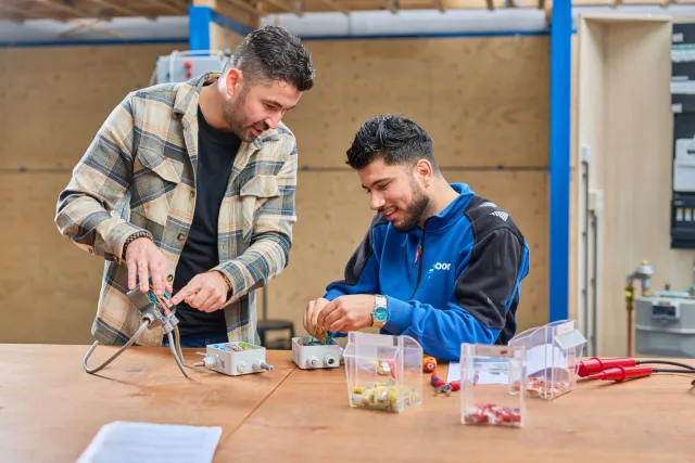 docent geeft uitleg aan student over elektrotechniek
