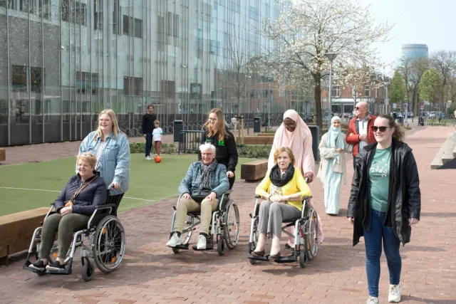 Studenten Persoonlijk Begeleider Maatschappelijke Zorg & Sociaal Werk lopen met cliënten buiten