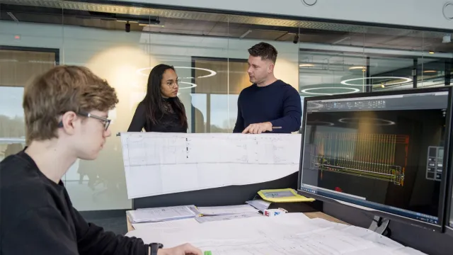Student werkt achter computer samen met andere student en docent