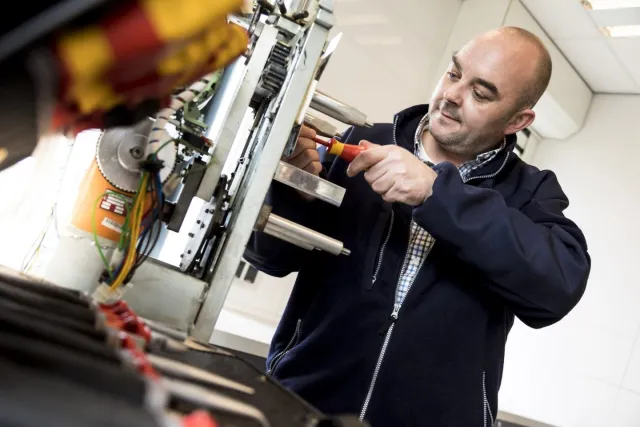 Student aan het werk bij een machine met een schroevendraaier