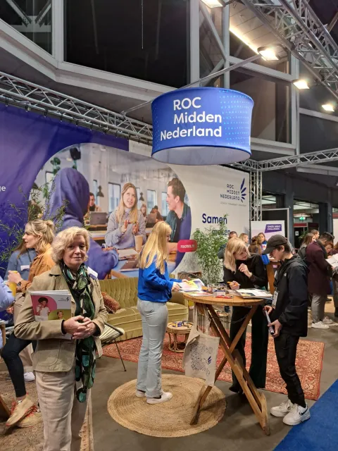 Student en voorlichter geven in de stand voorlichting aan studiekiezers