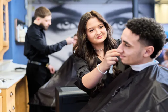 Student Barbier verzorgt baard van klant in schoolsalon