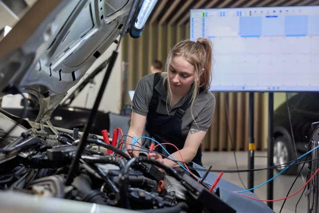 Student Autotechniek controleert elektriciteit onder de motorkap van een personenauto