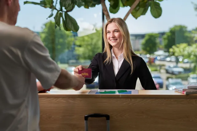 Gast geeft paspoort af bij balie tijdens inchecken