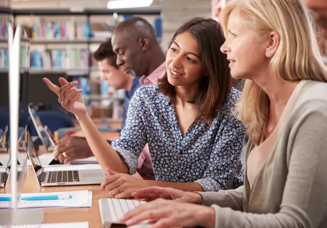 Een groep mensen werkt aan computers in een bibliotheek.