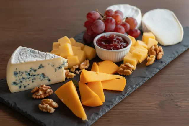 Kaasplank met verschillende soorten kaas, druiven en walnoten.