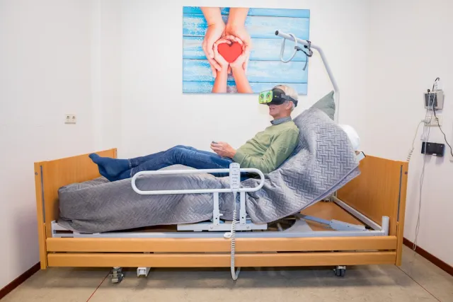 Een man met een VR-bril op zijn hoofd ligt in een ziekenhuisbed.