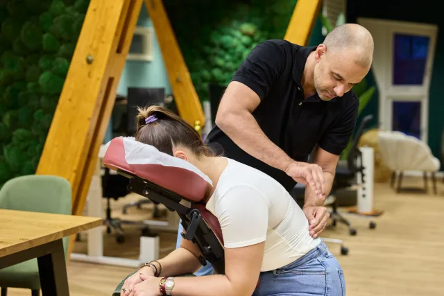 Een masseur geeft een vrouw een stoelmassage.