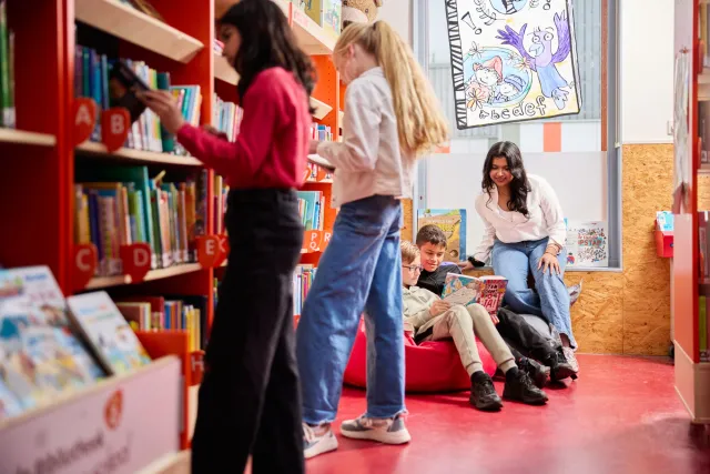 Student Onderwijsassistent leert kinderen lezen in de schoolbibliotheek